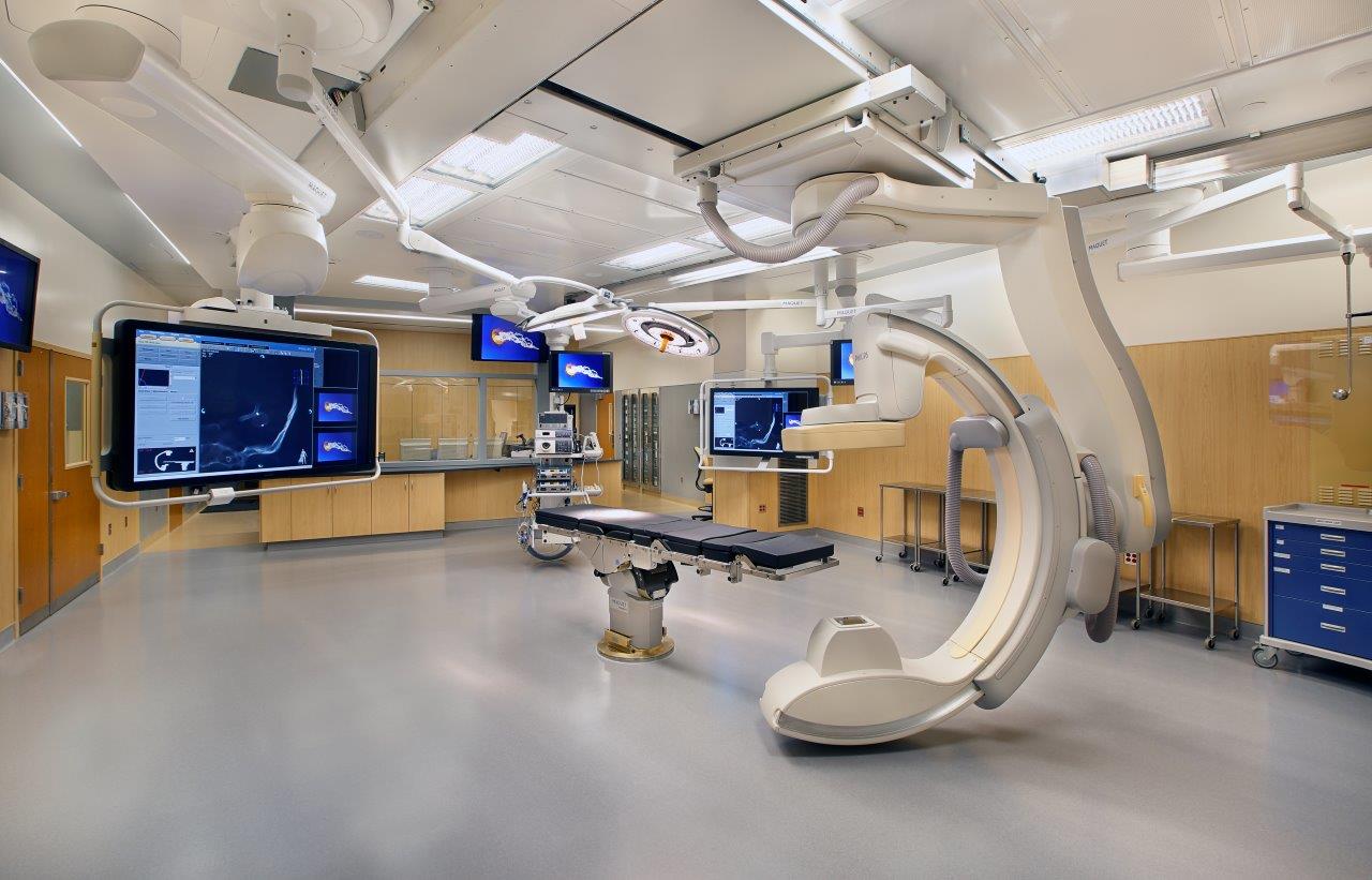 Hybrid operating room - image showing equipment in the large bright room. There are multiple monitors attached to equipment for doctors use.